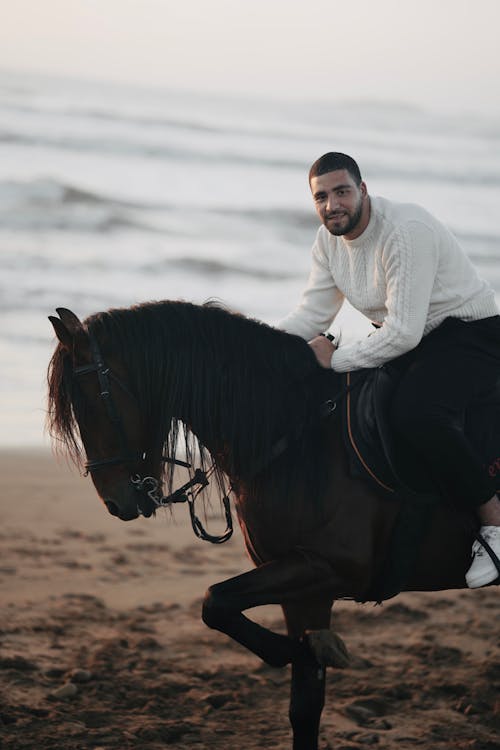 Man in White Sweater Posing on Horse