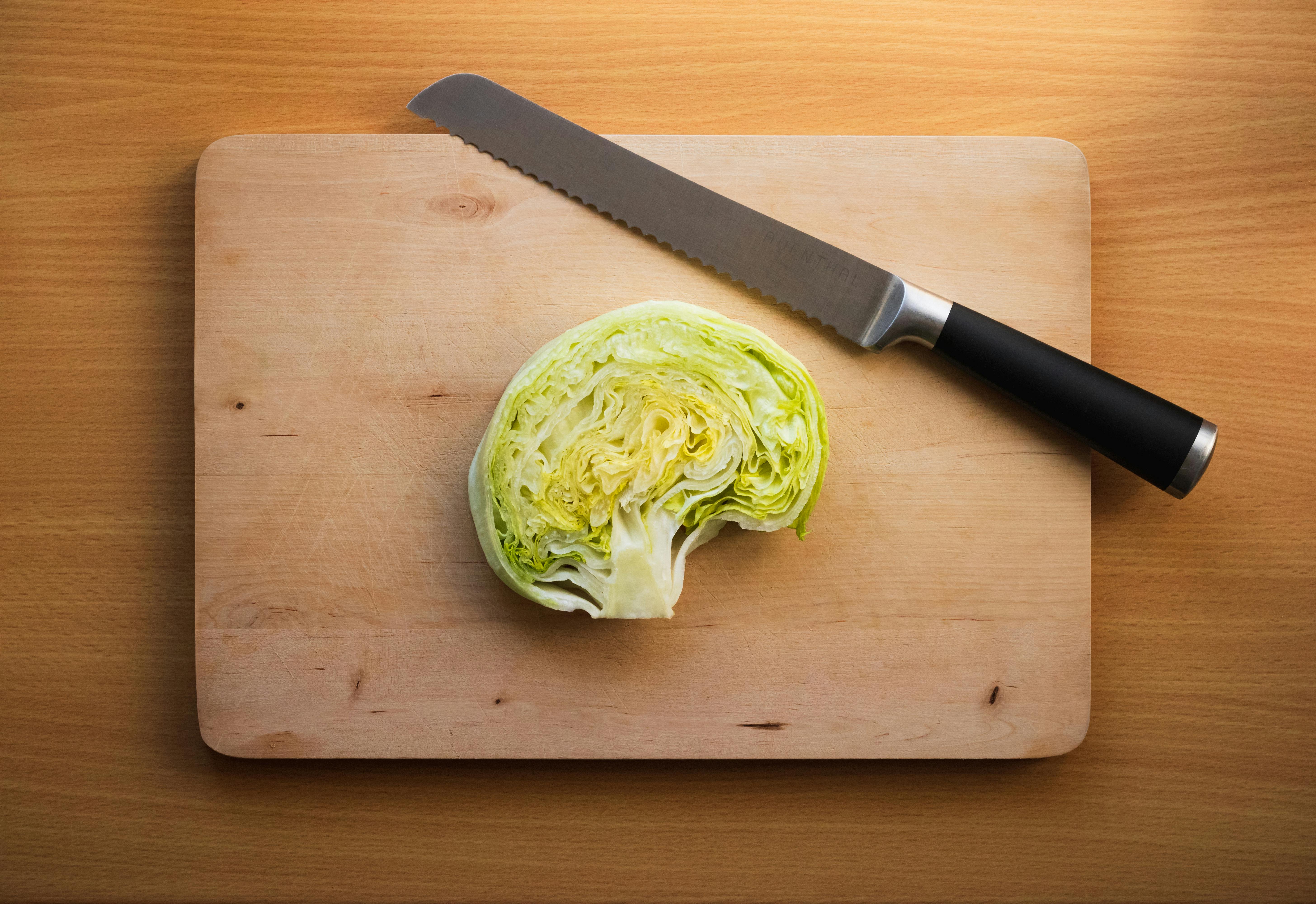 a knife and a cabbage on a cutting board