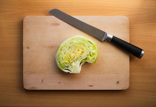 A knife and a cabbage on a cutting board