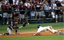 在欢呼的人群中，棒球运动员在一场热闹的比赛中戏剧性地滑回了本垒