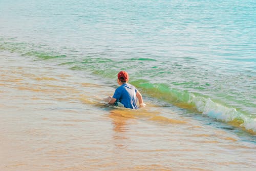 Free Photo of Boy Sitting on Shore at the Beach Stock Photo