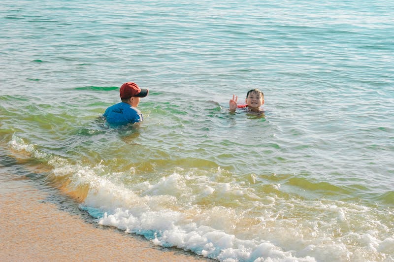 Children swimming and playing in clear shallow sea water at a sandy beach