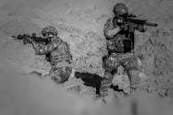 两名身着迷彩服和装备的士兵正在沙漠中执行战术行动