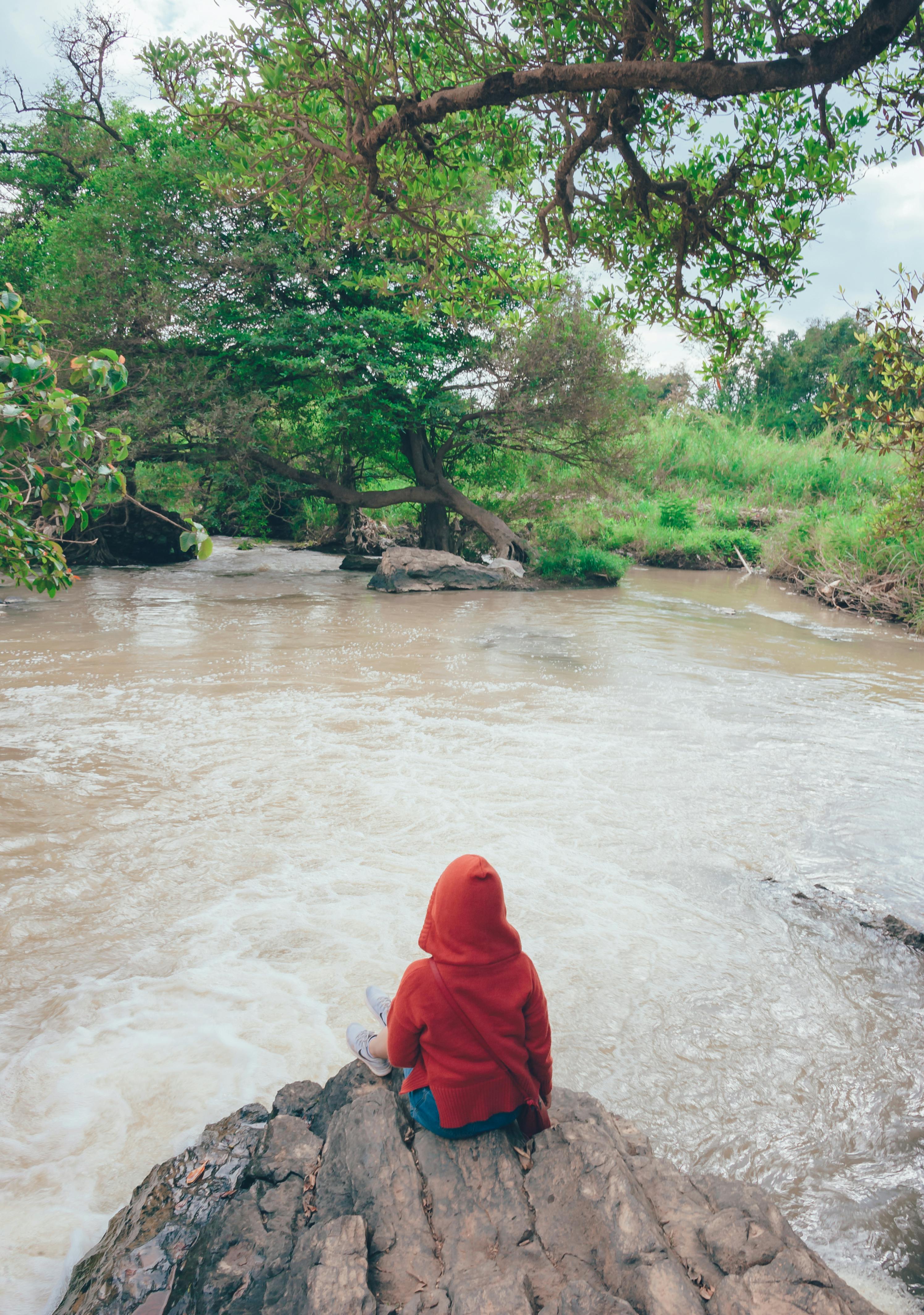 他坐在河边的岩石上，独自拥抱大自然的宁静