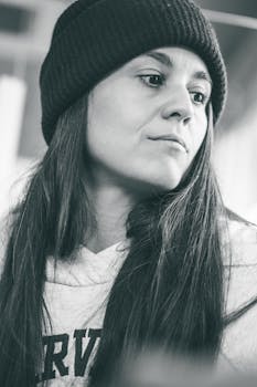 Black and white portrait of a woman with long hair wearing a beanie indoors.