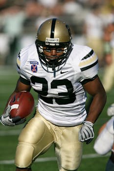 Focused American football player running with ball during game.