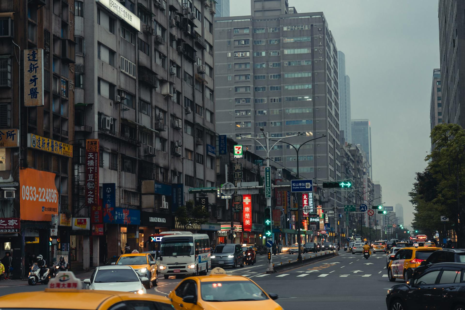 Bustling Taipei city street with taxis and skyscrapers, showcasing modern urban life.