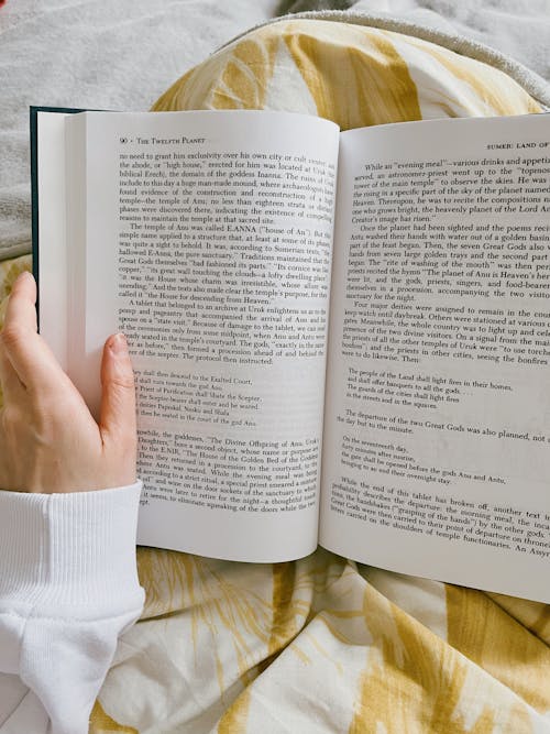 Woman Sitting in Bed and Reading a Book 