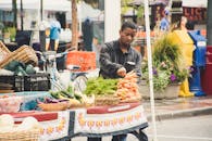 一名男子在街头市场的摊位上摆放新鲜蔬菜