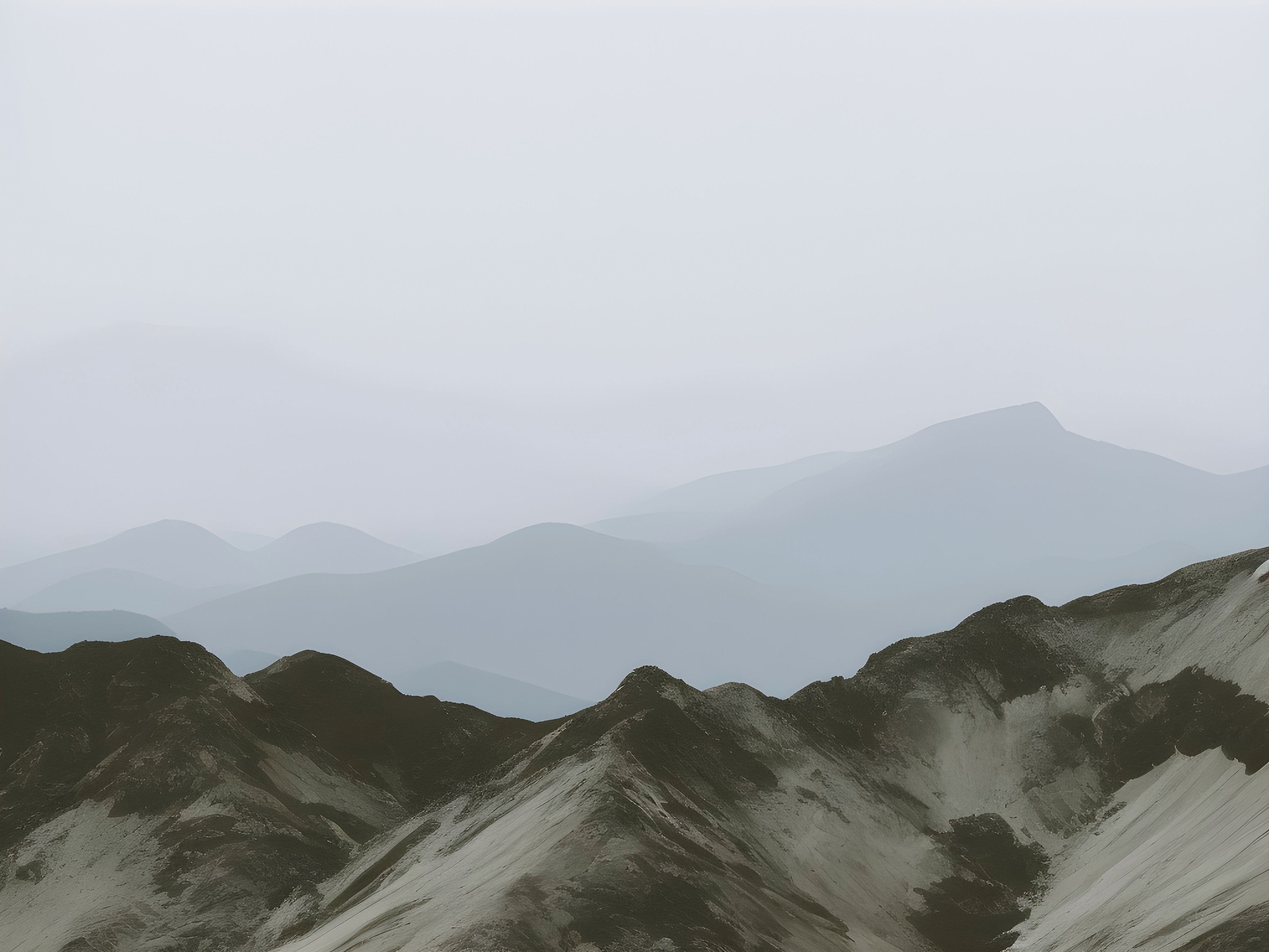 Serene foggy mountain range with soft gradients creating a tranquil atmosphere.