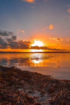 Beautiful golden sunset over a serene lake with vibrant reflections and dramatic clouds.