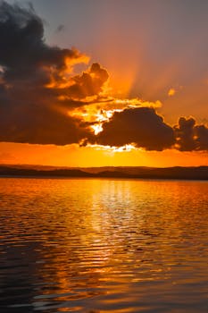 A stunning sunset with dramatic clouds reflecting on tranquil ocean waters.