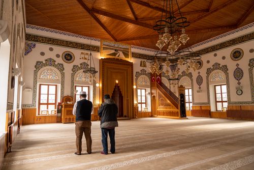 Free Two men praying inside an ornate mosque with stunning architectural details. Stock Photo