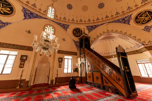 Free A man praying inside an ornate mosque with intricate designs and chandeliers, symbolizing Islamic faith. Stock Photo