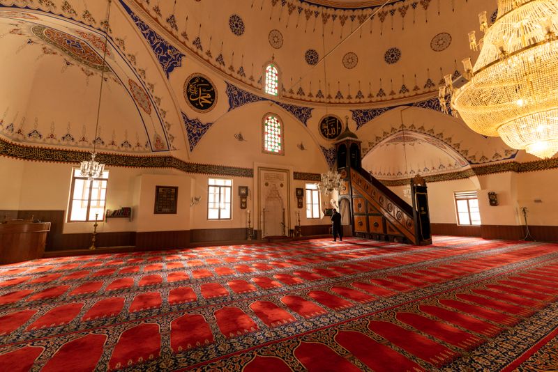 Elegant mosque interior showcasing intricate designs, chandeliers, and vibrant red carpets