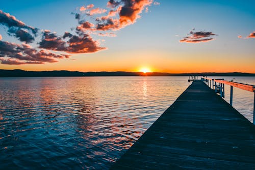 A pier at sunset with clouds and water