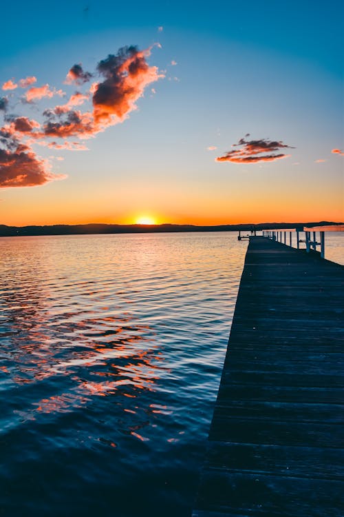 A wooden pier with clouds and water at sunset