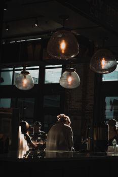 Warm atmosphere in an urban cafe with unique lighting and people enjoying their coffee.