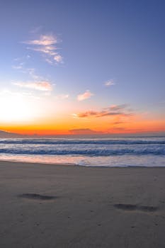 A peaceful beach scene during sunset with colorful skies and gentle waves.