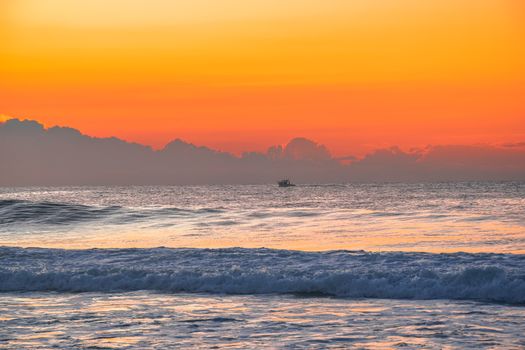 Stunning sunset over the ocean with vivid colors and gentle waves, creating a peaceful seascape.