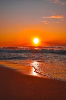 Stunning ocean sunrise with vivid colors reflecting off the gentle waves and sandy beach.