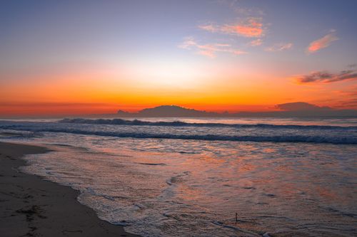 Free A beautiful sunrise over a tranquil ocean scene with vibrant colors reflecting on the water. Stock Photo
