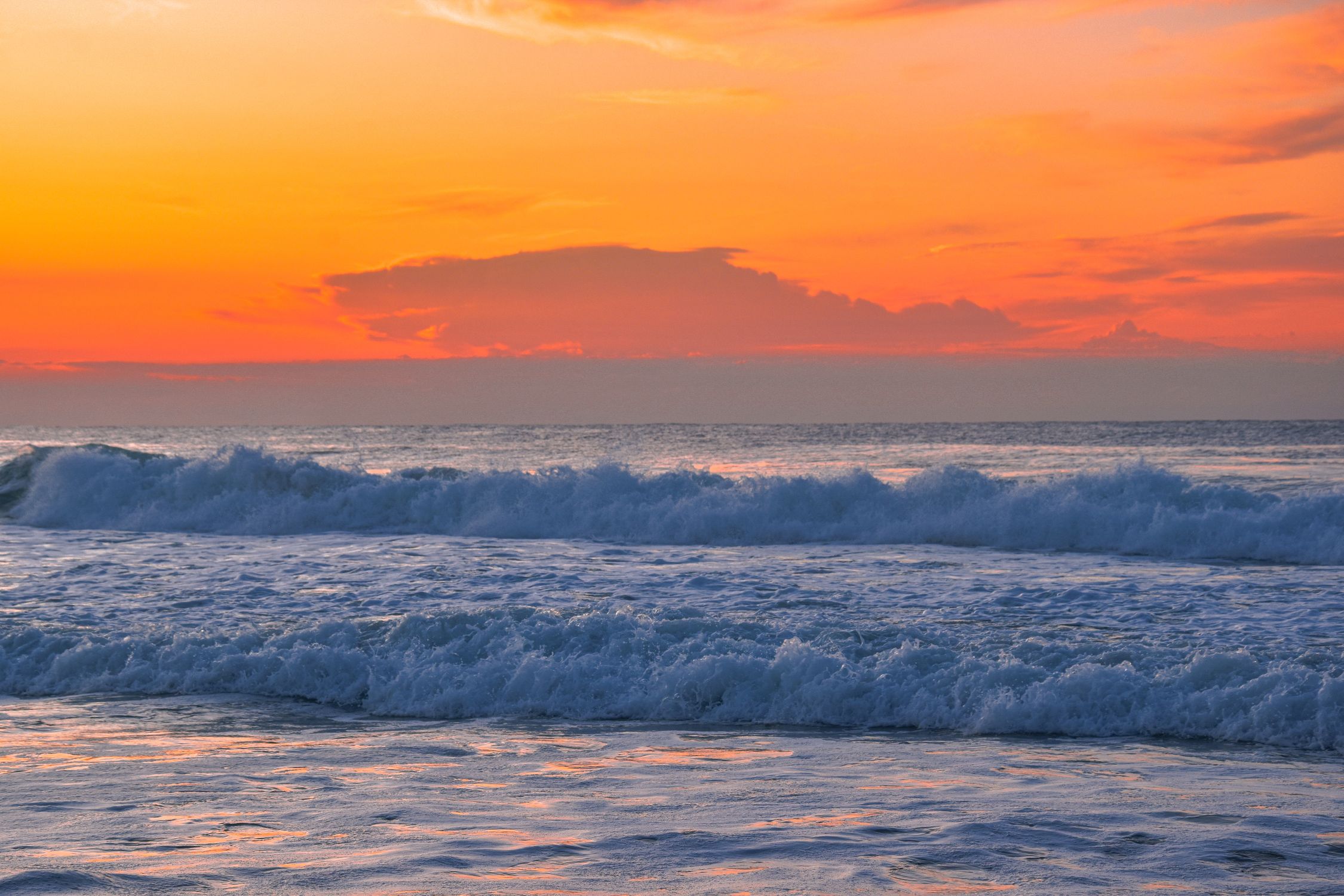 A sunset over the ocean with waves crashing · Free Stock Photo