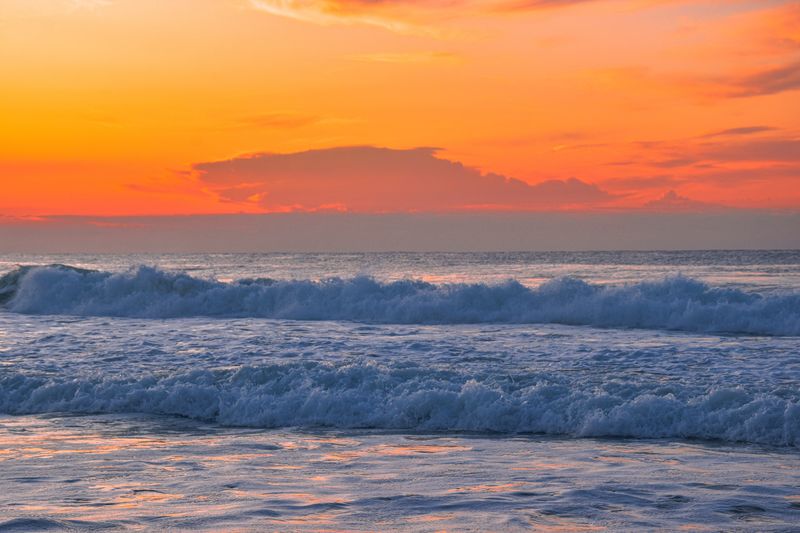 A sunset over the ocean with a large wave · Free Stock Photo