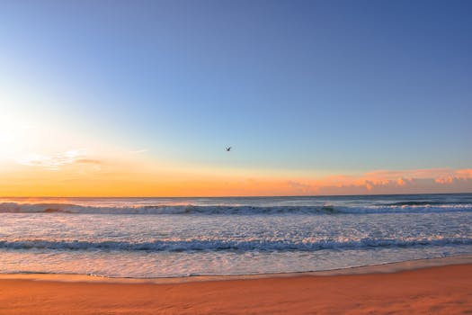 A serene sunrise over a peaceful beach with vivid sky colors and gentle waves.
