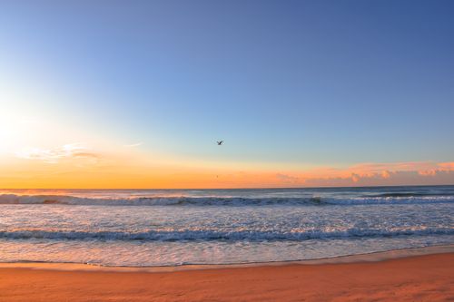 Free A serene sunrise over a peaceful beach with vivid sky colors and gentle waves. Stock Photo