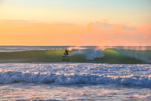 A surfer enjoys a thrilling ride on a wave during a vibrant sunset by the sea.