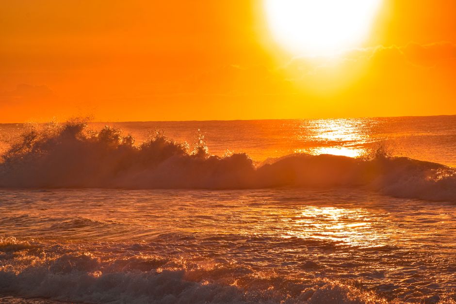 Vibrant sunset over ocean waves creating a serene and tranquil beach scene.