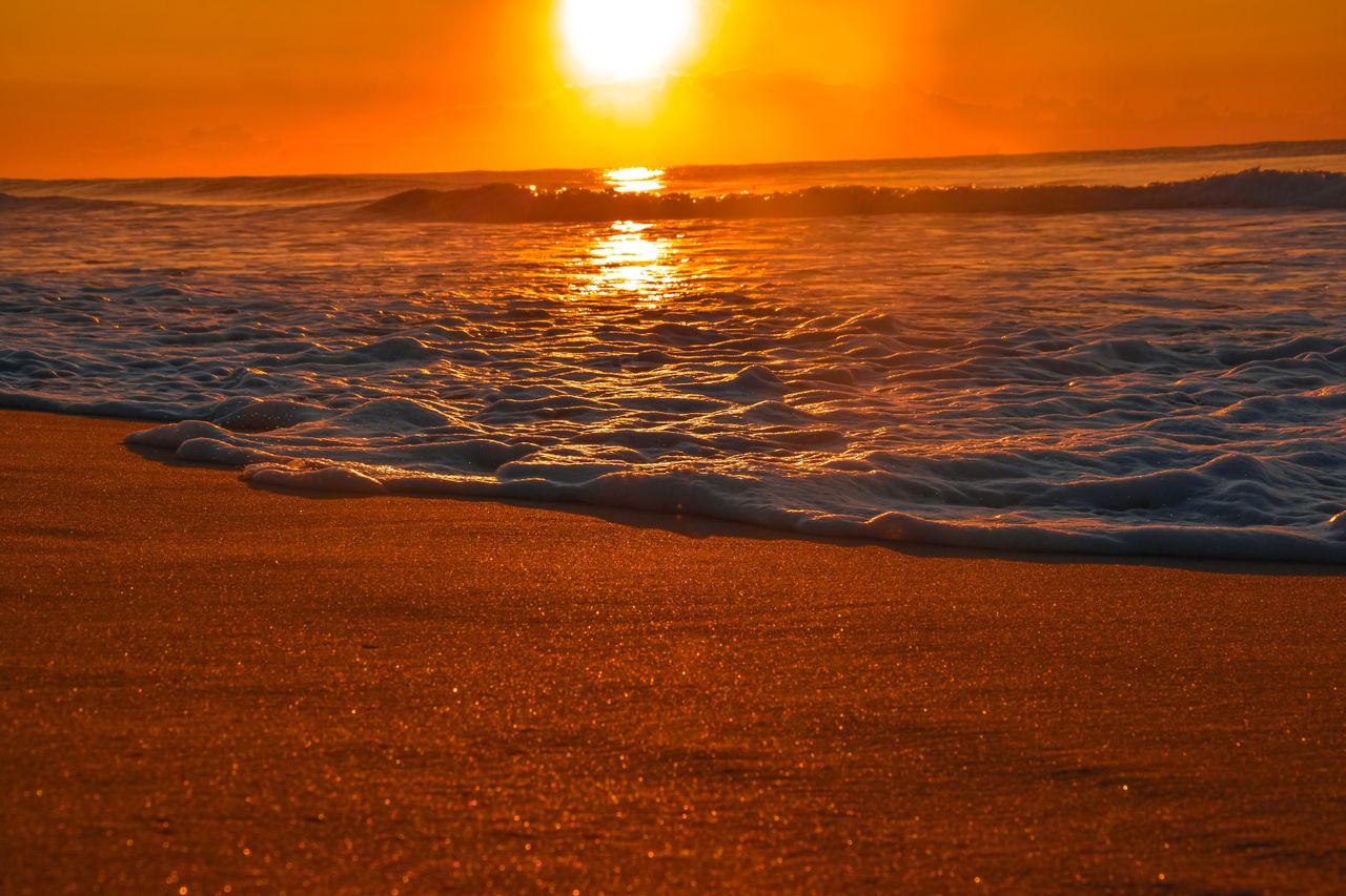 experience peace with a stunning golden sunset over a serene beach cap