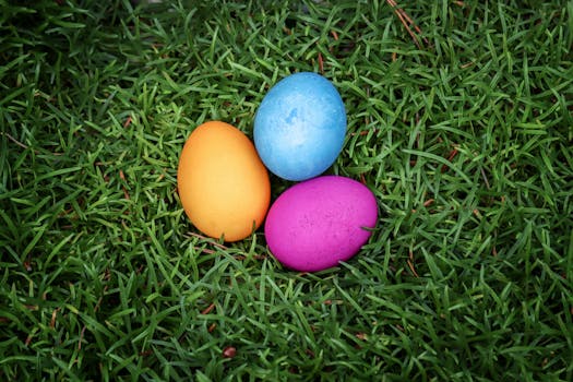 Colorful Easter eggs in blue, yellow, and pink resting on lush green grass.