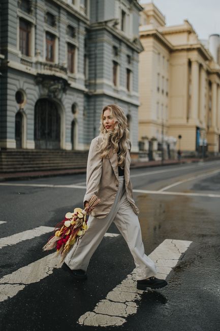 Elegant woman crossing the street with a vibrant autumn bouquet in an urban setting.