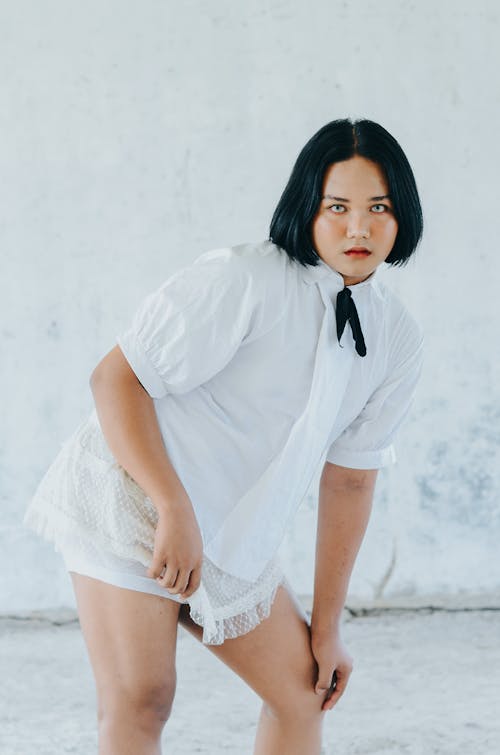 Young Brunette in White Shirt and White Shorts Posing in Studio 