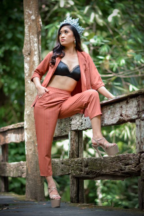 Free Fashionable woman in suit and tiara posing on a wooden bridge in a lush forest setting. Stock Photo