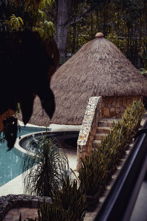 Free Explore a serene outdoor space featuring a thatched hut and swimming pool surrounded by lush greenery. Stock Photo