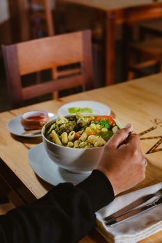 Delicious pasta bowl with fresh vegetables on a restaurant table.