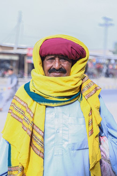 Free Portrait of a man in traditional attire with a yellow turban in Khairpur Tamewali, Pakistan. Stock Photo