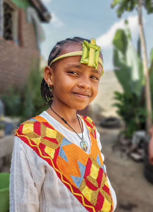 Free Child wearing traditional colorful clothing and headpiece, smiling warmly outdoors. Stock Photo