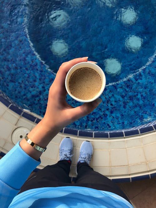 Woman Holding a Cup over the Swimming Pool 