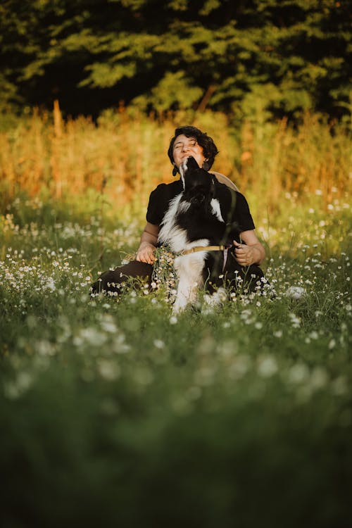 A Man Sitting on a Grass Field with the Dog 