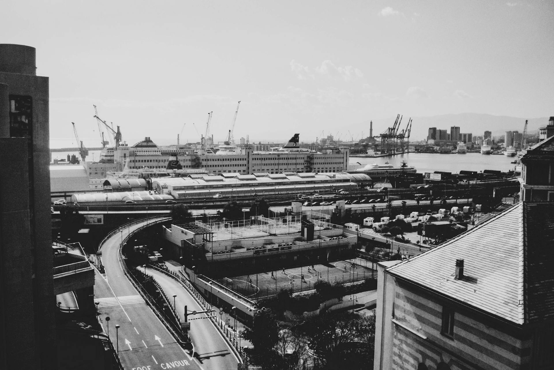 Black and white view of Genoa's bustling port with cranes and ships showcasing modern architecture.