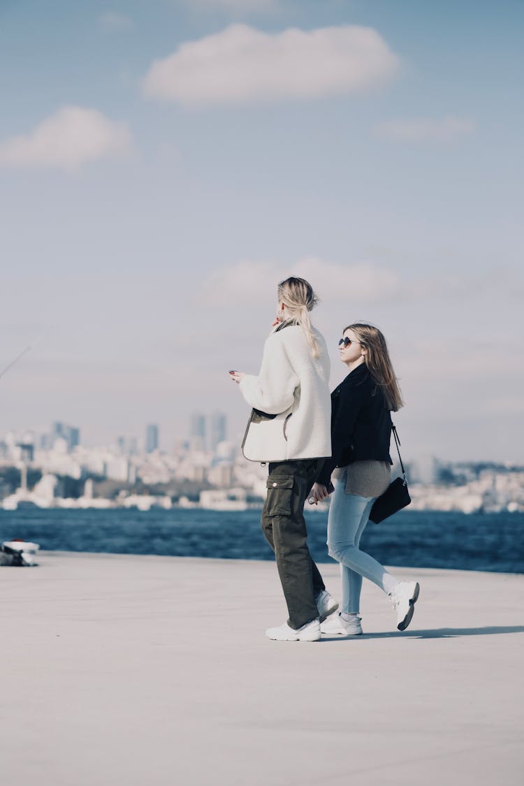 Two Girls Walking On A Promenade 