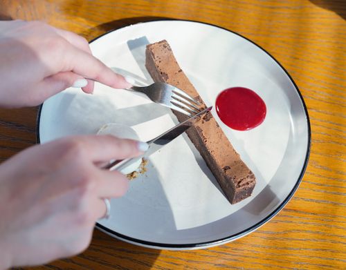 Free A chocolate dessert on a plate being cut with cutlery, accompanied by red sauce. Stock Photo