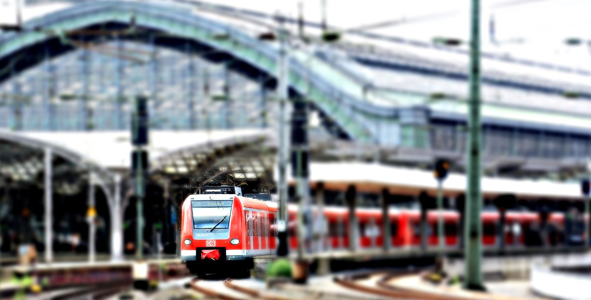 Red train arriving at a sleek, contemporary railway station. Urban transport hub.