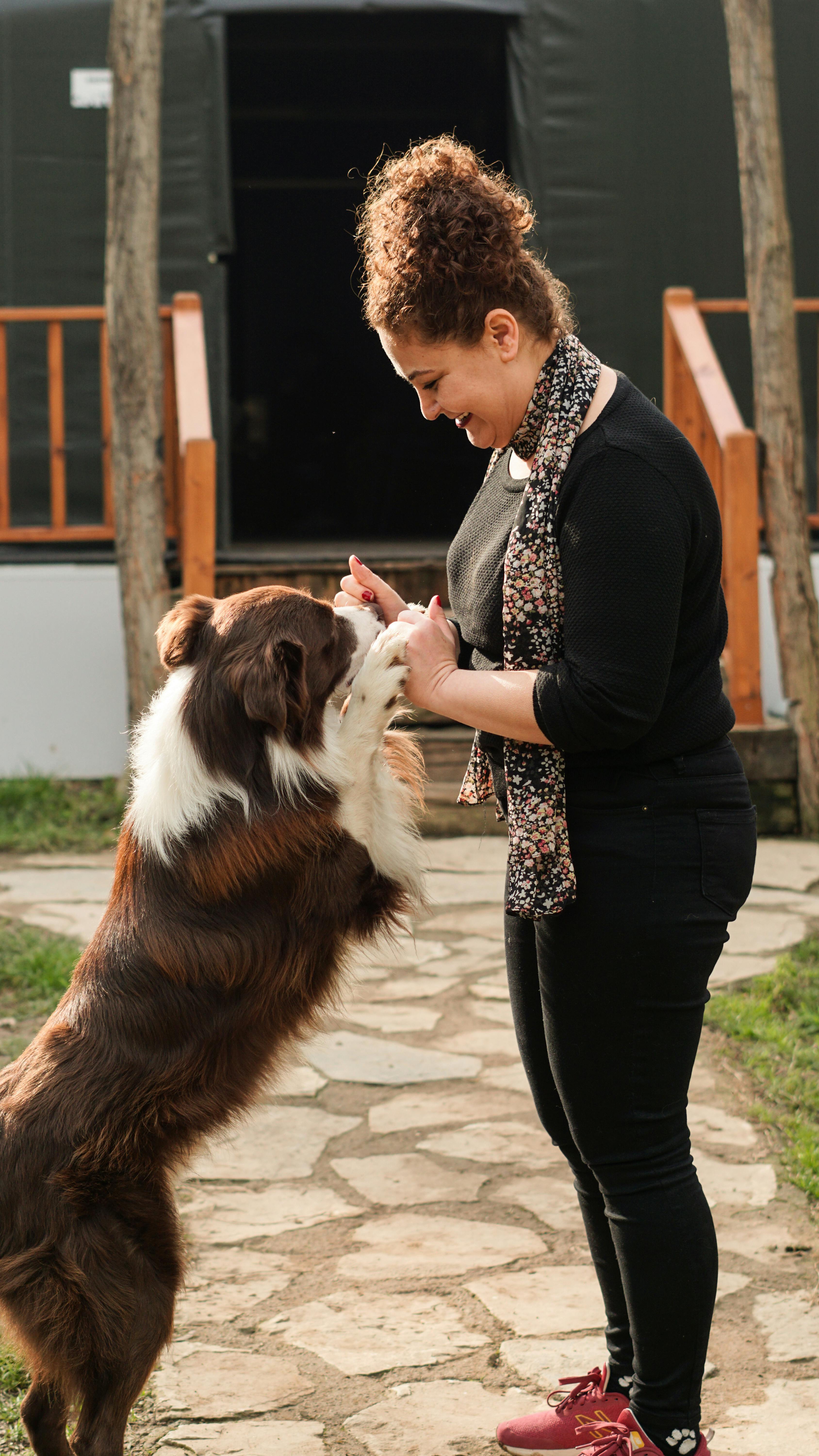 A woman playing with a dog in a yard