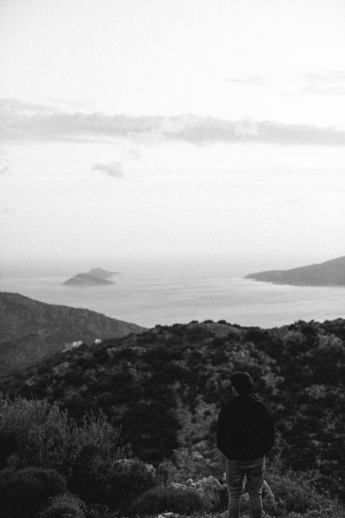 Free A lone traveler gazes at the tranquil ocean from a mountain, invoking peace. Stock Photo