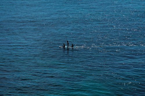 Free Three surfers on the ocean waves of San José del Cabo, Mexico, under the midday sun. Stock Photo